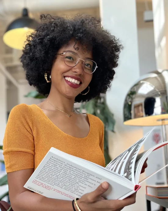 Tanicia Bethea, holding an open book, and smiling